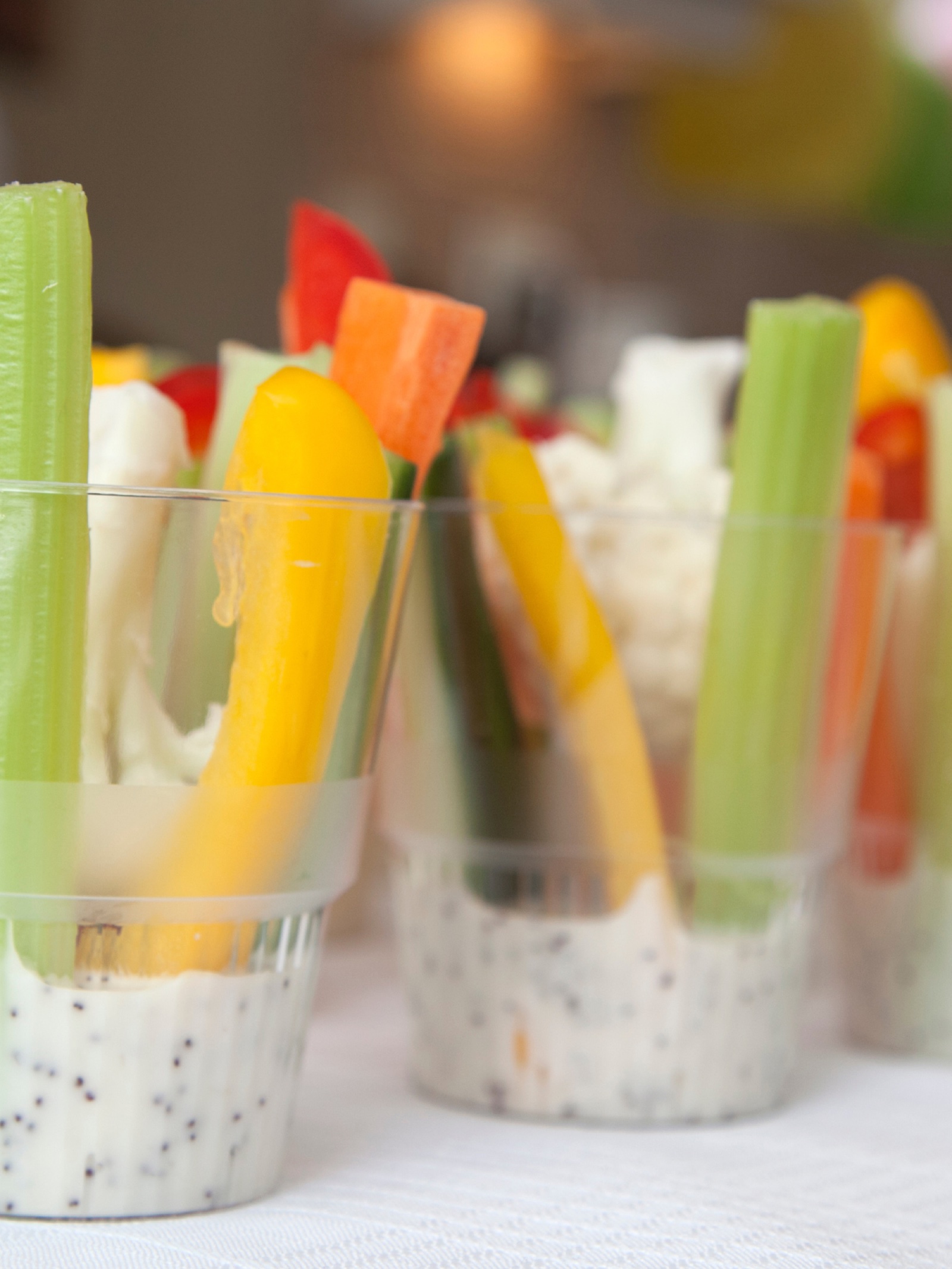 Small cups of veggie sticks — celery, carrot, yellow pepper, and cauliflower — served with dip.