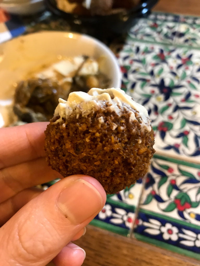 Falafel dipped in hummus, on a mosaic background.