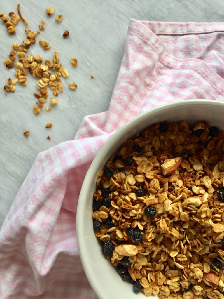 Close-up of vanilla, almond and coconut granola on a pink towel, on a marble background.