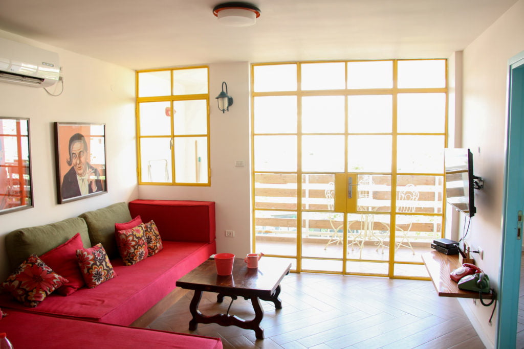 Golda Vacation Rentals 'Yellow Apartment' in Jerusalem: Red couch, and yellow window sills, wooden floor boards.