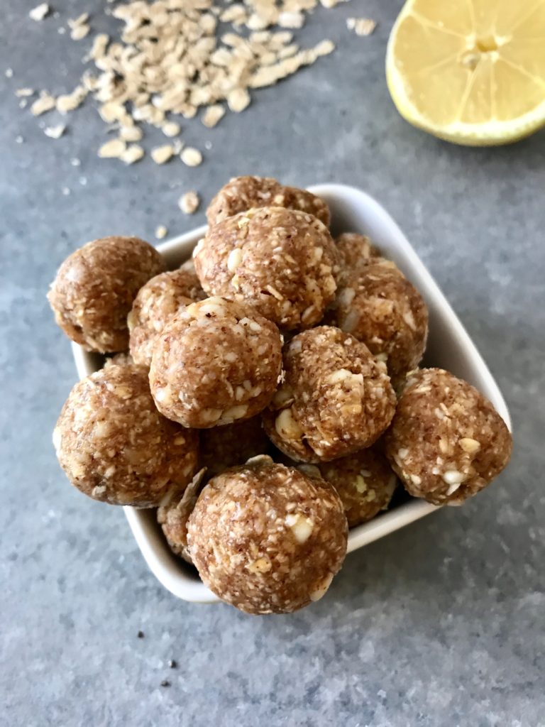 White chocolate and lemon energy bites in a white bowl on a gray background.