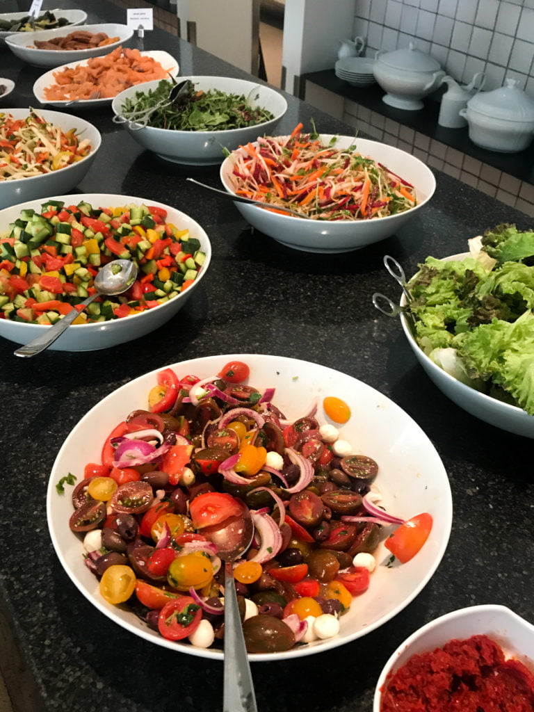6 big salads in white bowls at the Mamila Hotel breakfast buffet.