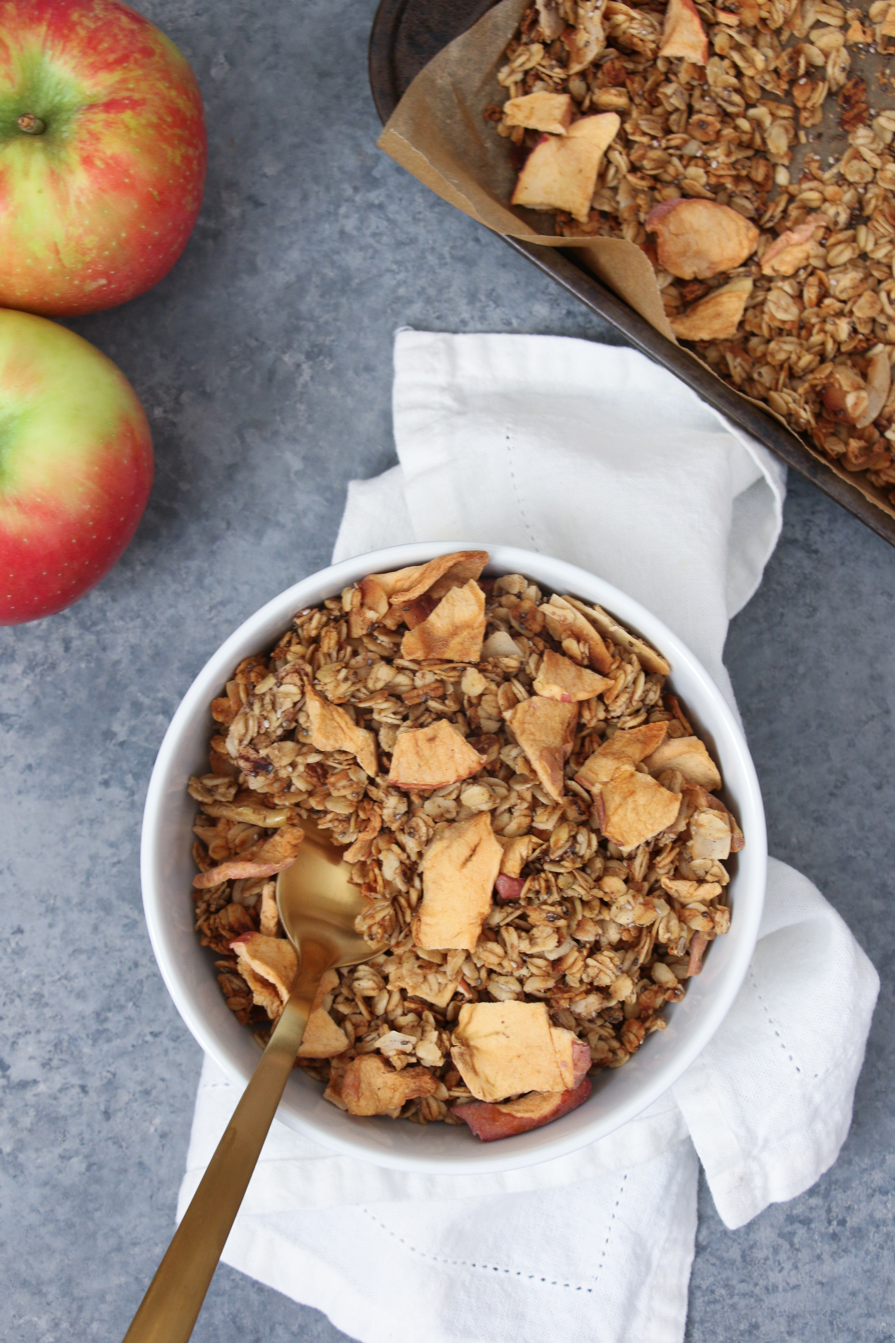 Apple-cinnamon granola in a white bowl on gray background