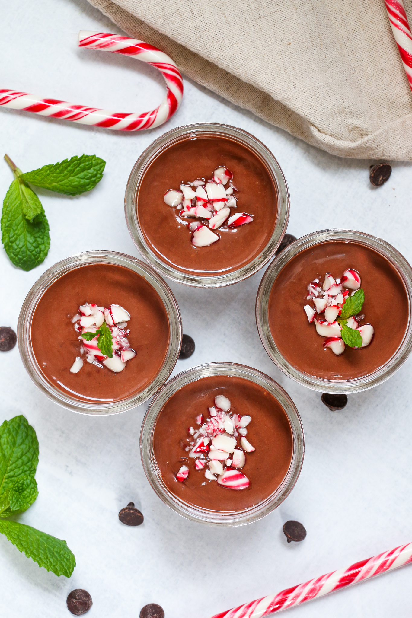 4 mini chocolate-mint cheesecake pots, topped with candy canes, on a white background