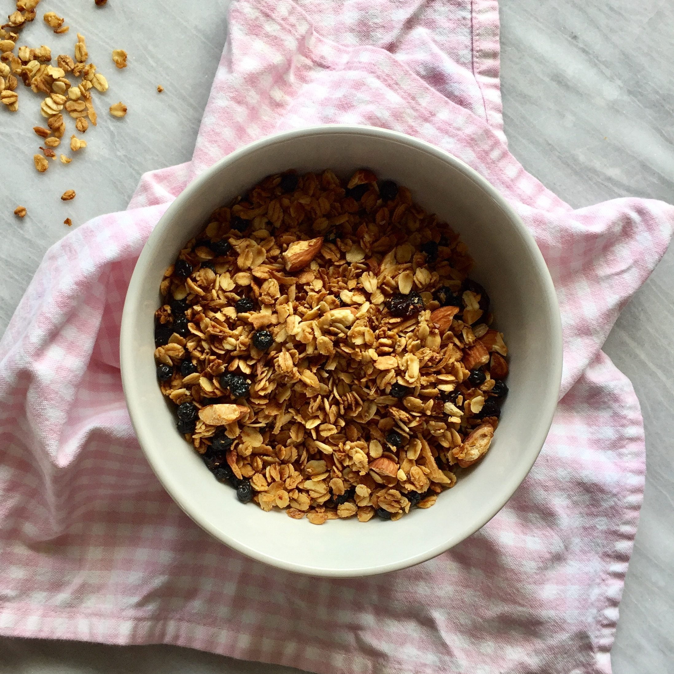 Vanilla, almond, and coconut granola on a pink towel on a marble background